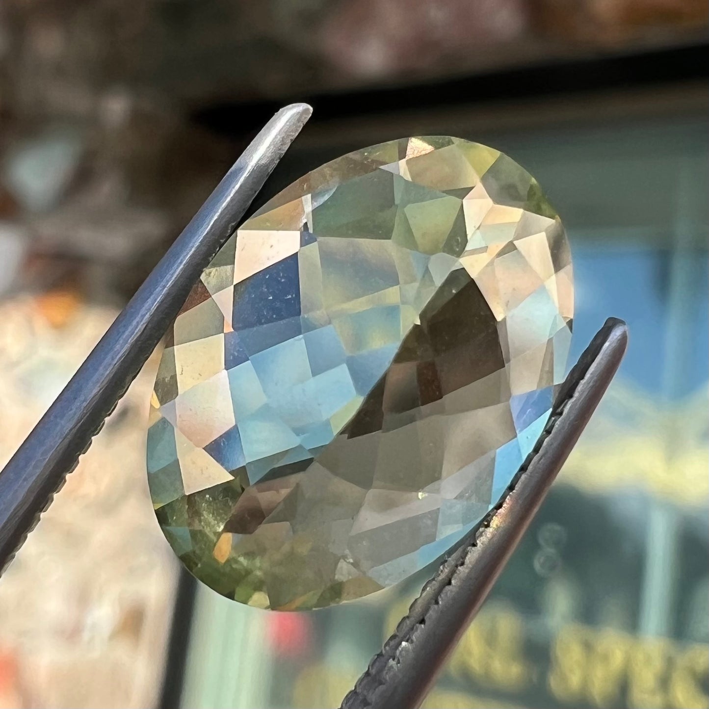 An oval checkerboard cut kiwi mystic topaz gemstone. The stone is a light yellowish green color.