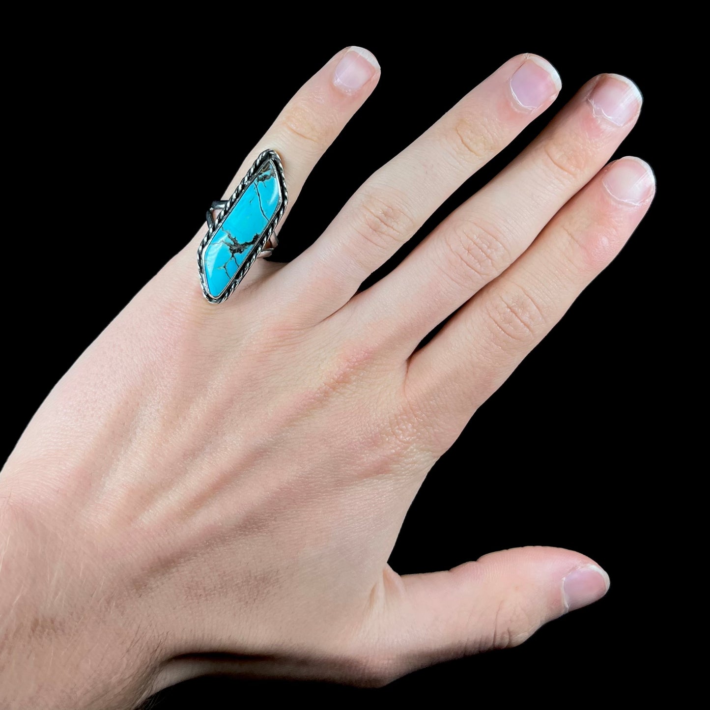 A vintage, Southwest style sterling silver ring set with a natural turquoise stone. The stone is blue with a black matrix.