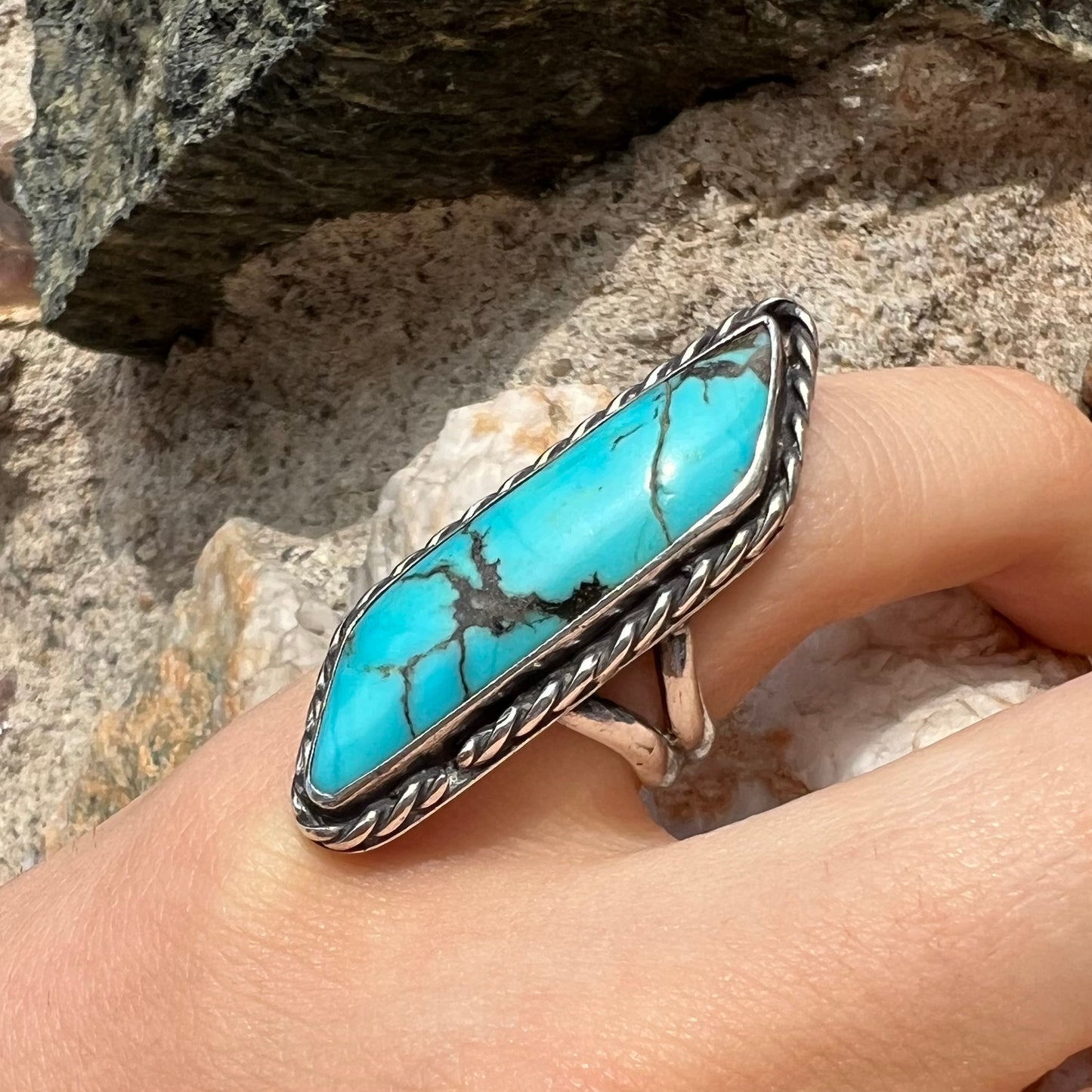 A vintage, Southwest style sterling silver ring set with a natural turquoise stone. The stone is blue with a black matrix.