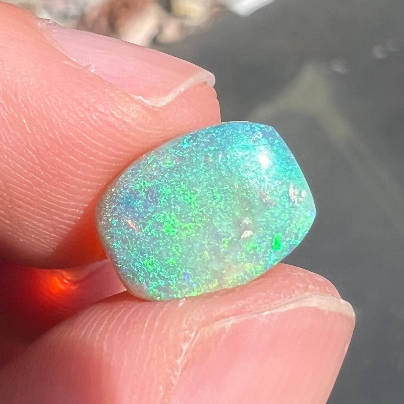 A 2.40ct barrel shaped Lightning Ridge semi-crystal opal. The stone has blue and green colors.