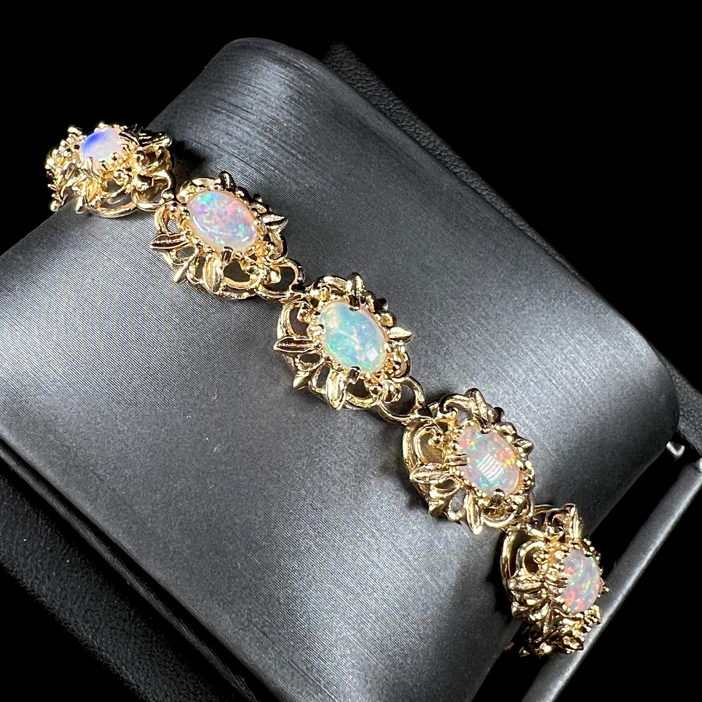 A ladies' yellow gold bracelet set with natural, oval cabochon cut white crystal opals.