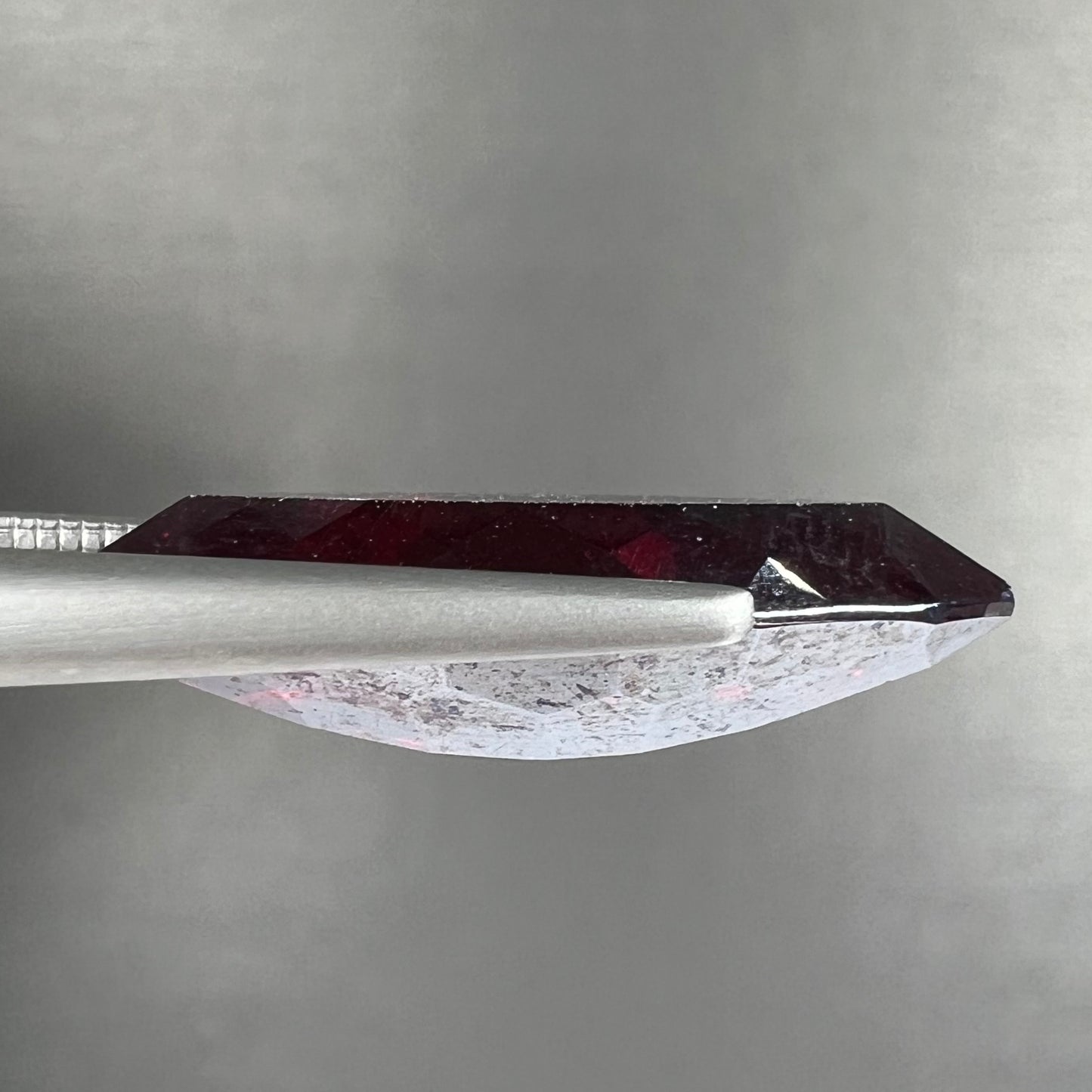 A loose, marquise cut cuprite gemstone. The stone is a deep, crimson red color.