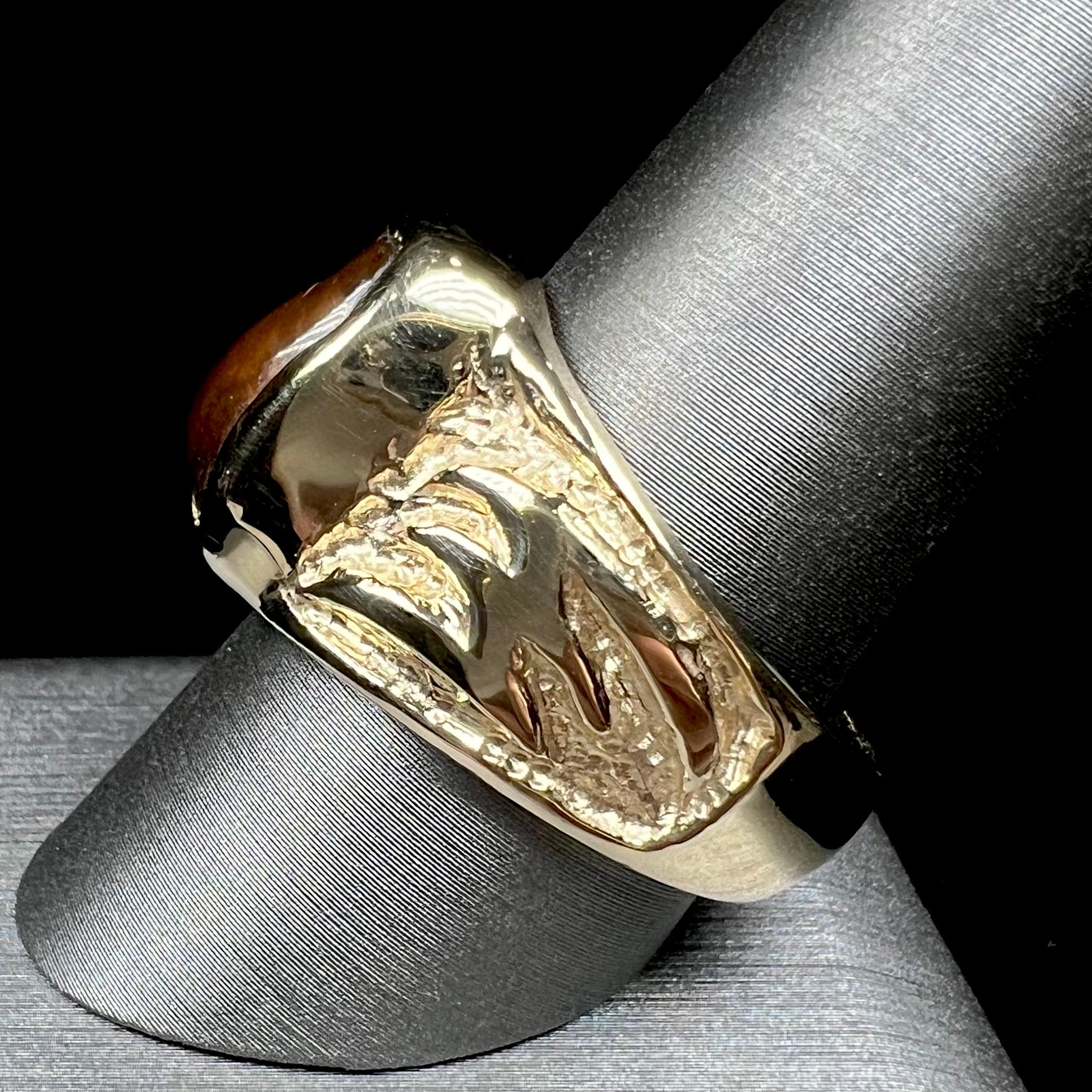 A man's yellow gold solitaire ring set with a freeform shaped Mexican fire agate stone.  The stone has a purple bull's eye pattern.
