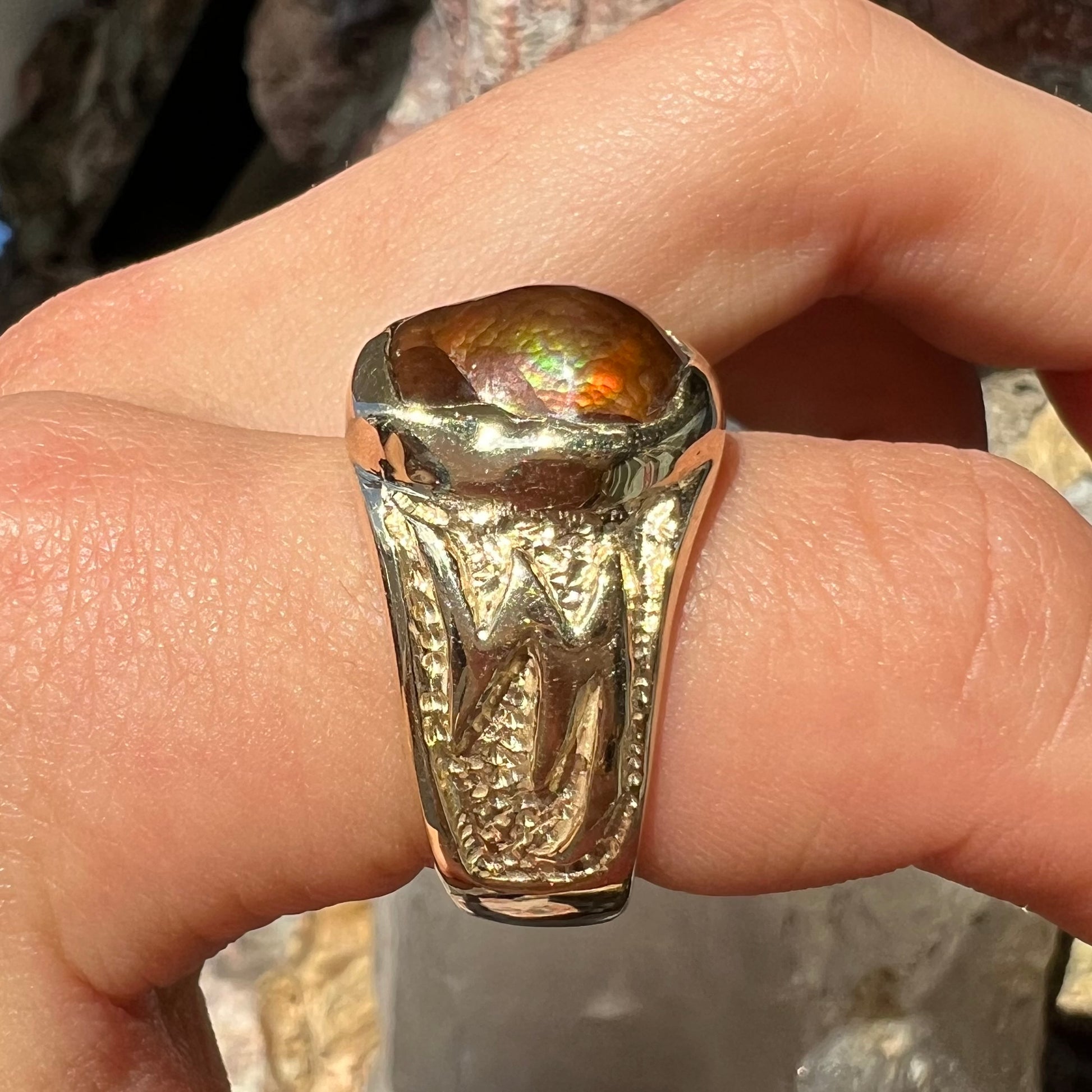 A man's yellow gold solitaire ring set with a freeform shaped Mexican fire agate stone.  The stone has a purple bull's eye pattern.