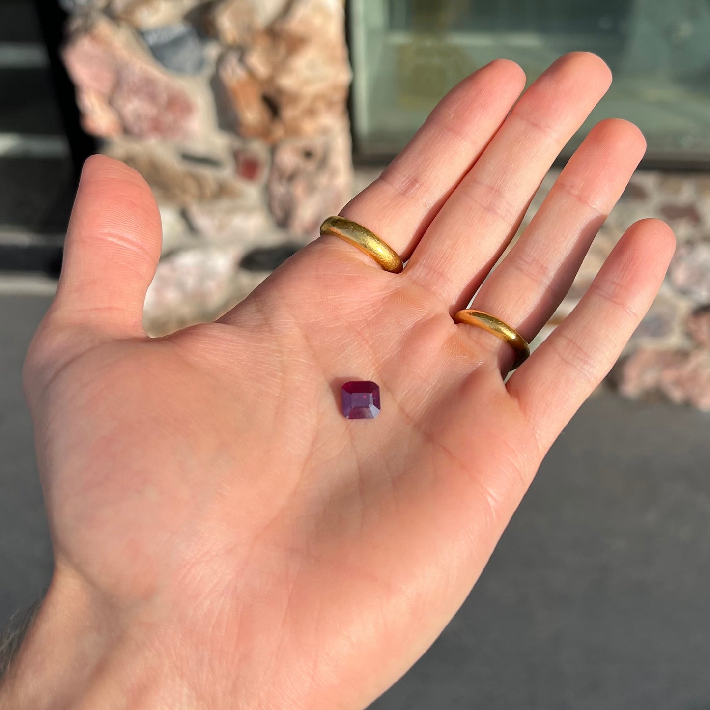A loose, modified Asscher cut cuprite gemstone. The stone is a deep, crimson red color and has several chips along the girdle.