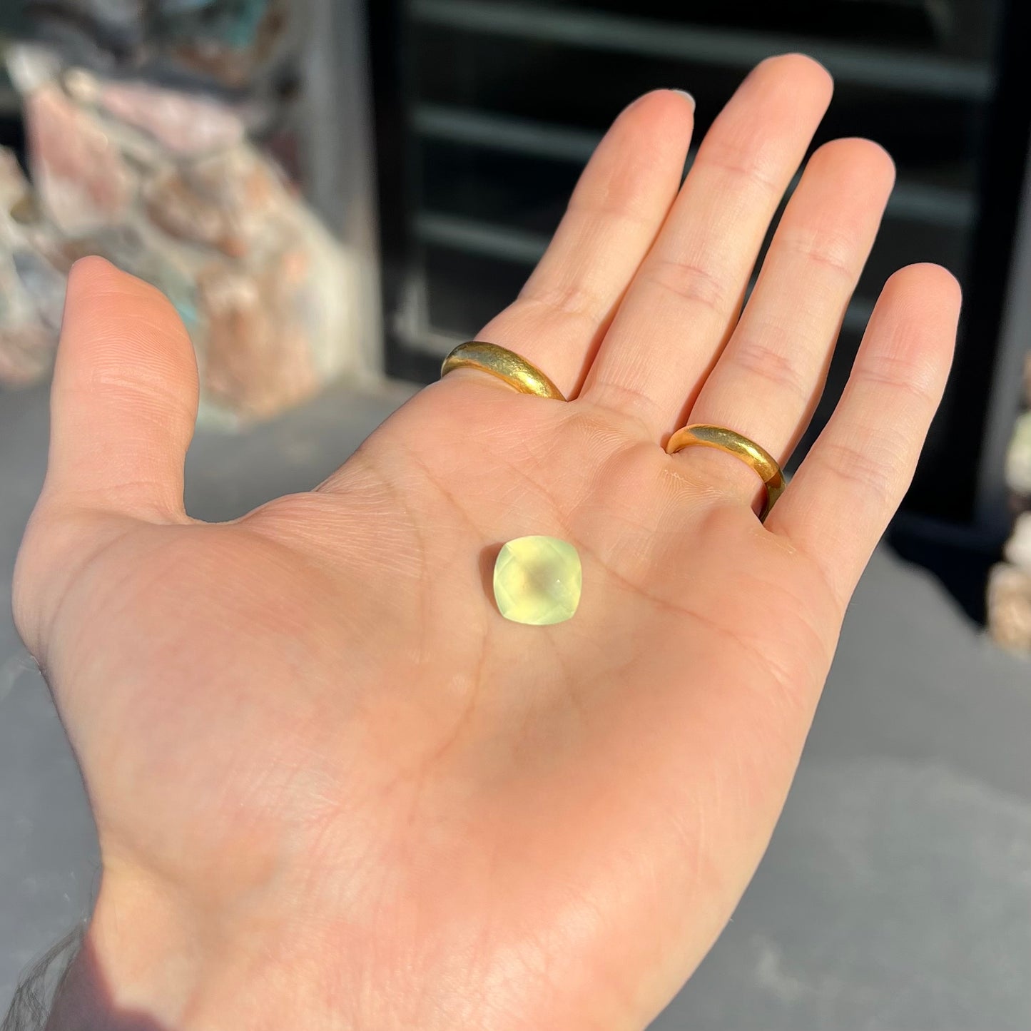 A loose, checkerboard cushion cut prehnite gemstone. The stone is a sleepy yellow green color.
