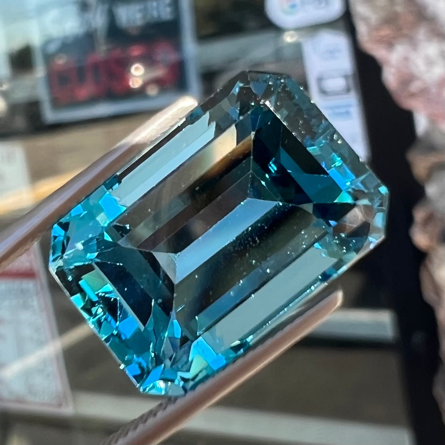 A loose, emerald cut London blue topaz gemstone. The stone is a deep, dark blue color.