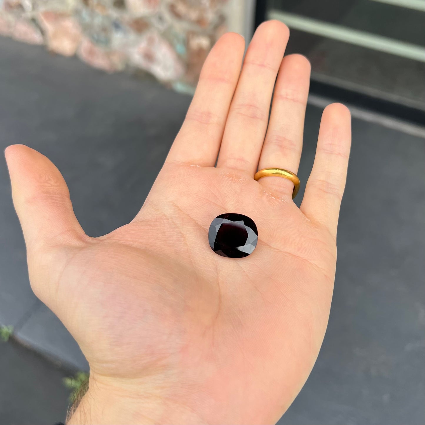 A loose, faceted oval cut rubellite tourmaline gemstone. The stone is a dark purple red color.