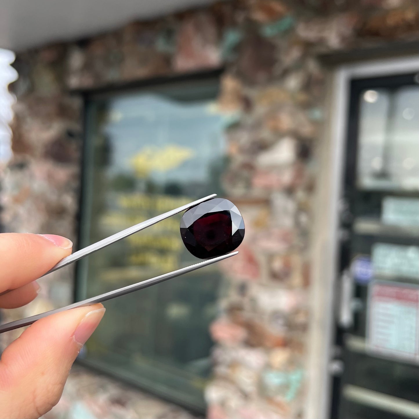A loose, faceted oval cut rubellite tourmaline gemstone. The stone is a dark purple red color.