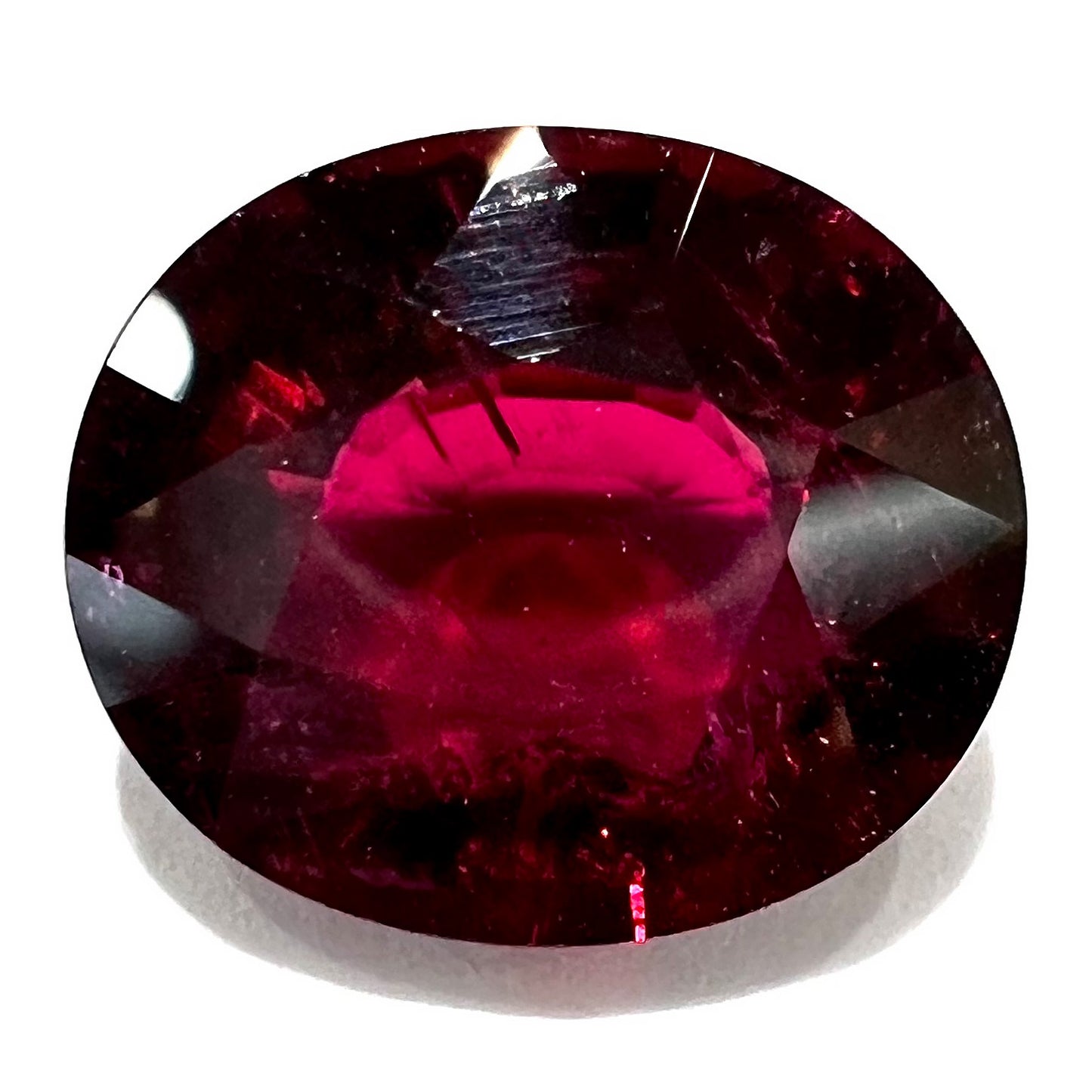 A loose, oval cut purplish red rubellite tourmaline stone.