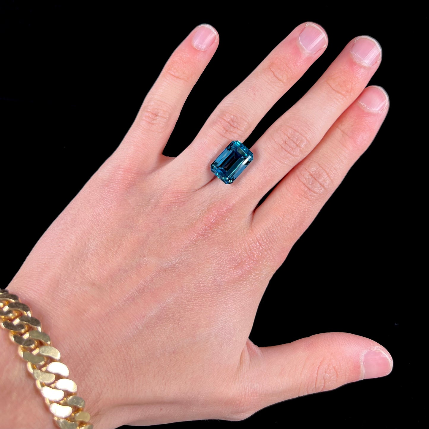 A loose, emerald cut London blue topaz gemstone. The stone is a deep, dark blue color.