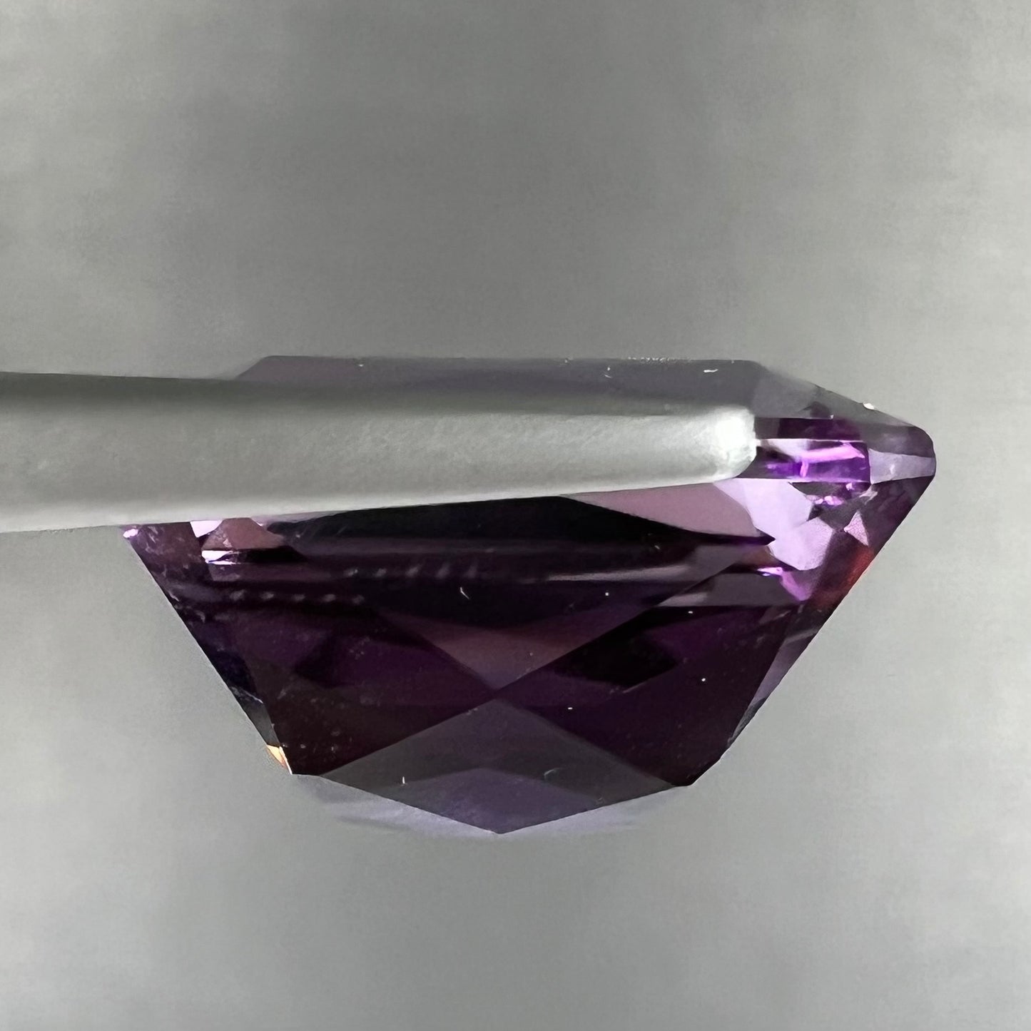 A loose, modified radiant cut amethyst stone.