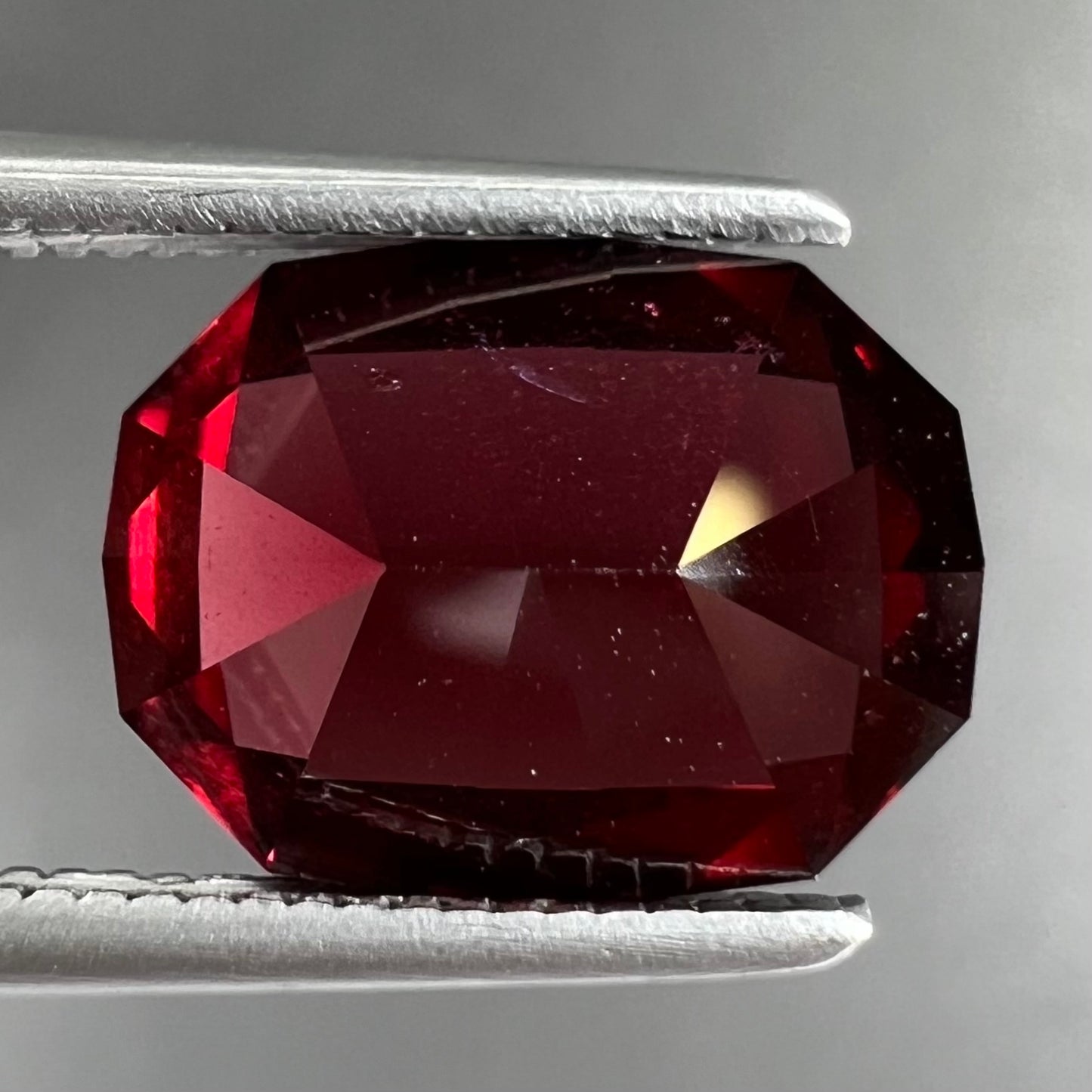 A loose, octagon cut rhodolite garnet gemstone. The stone is a deep, purplish crimson red color.