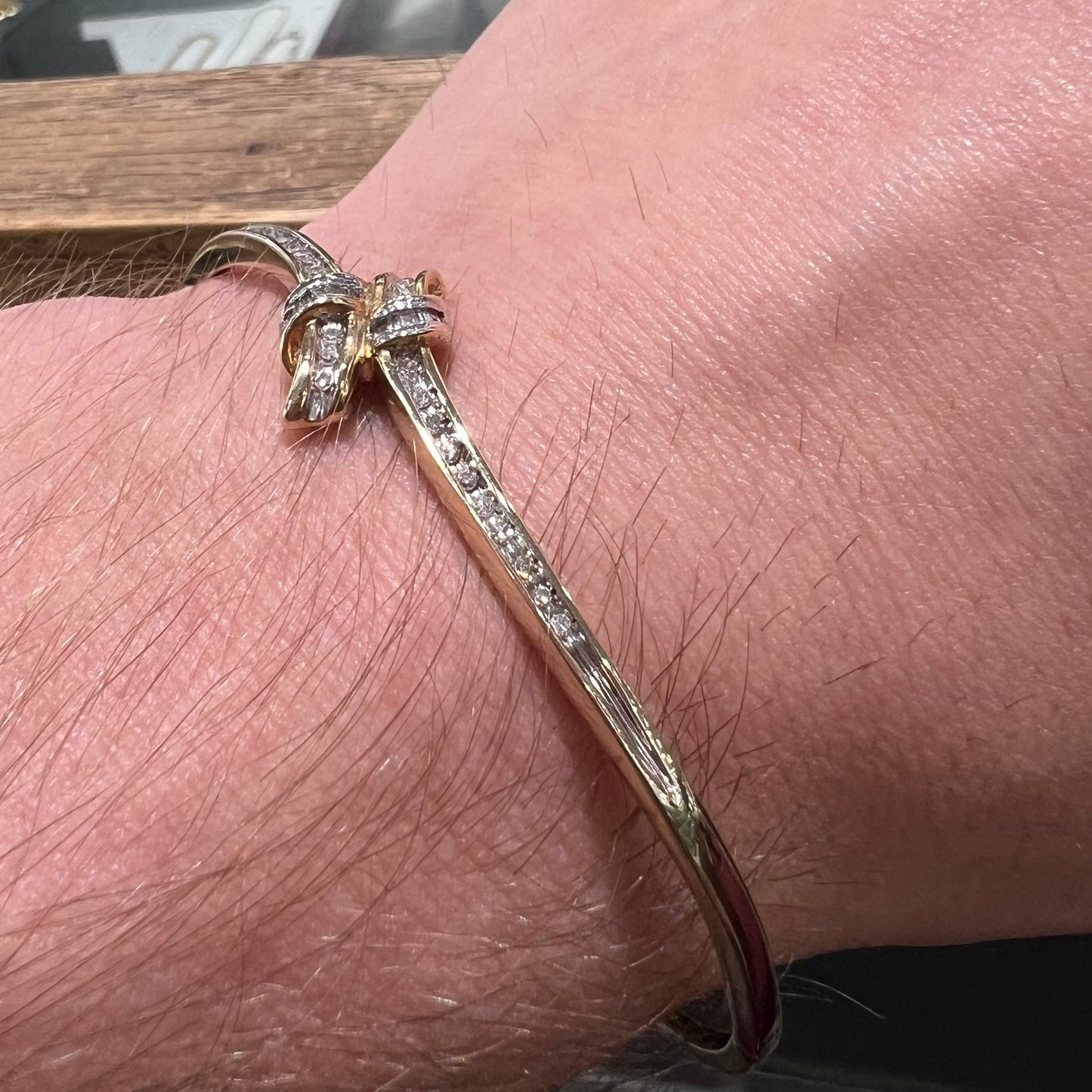 A ladies' knot style yellow gold bangle bracelet set with round and baguette cut diamonds.