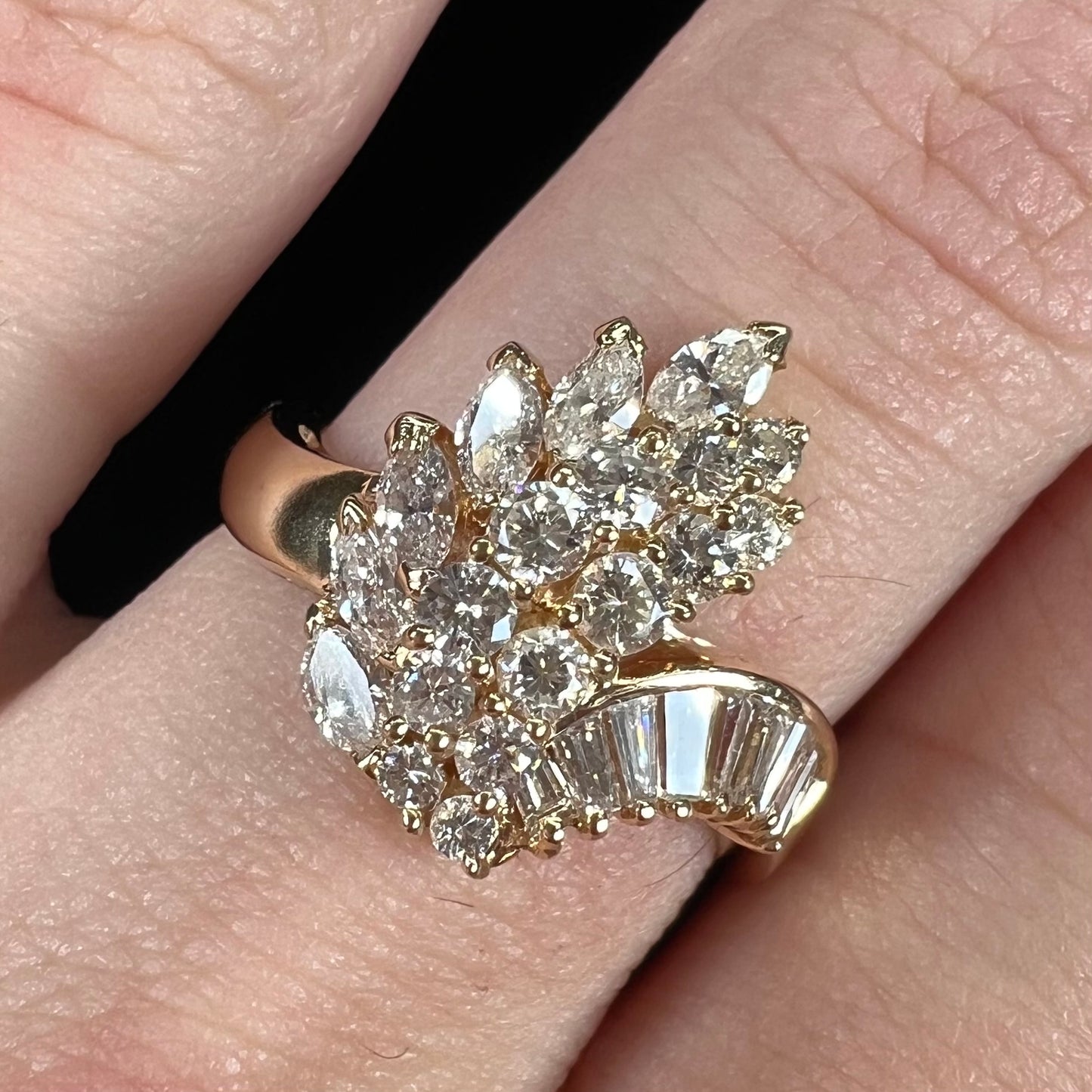 A yellow gold diamond cluster ring set with round, marquise, and baguette cut diamonds.