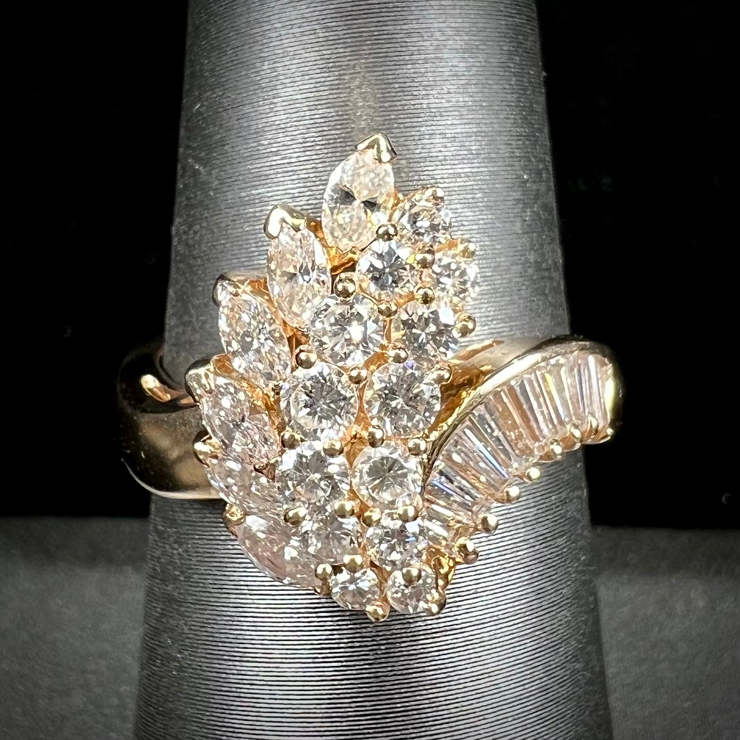 A yellow gold diamond cluster ring set with round, marquise, and baguette cut diamonds.