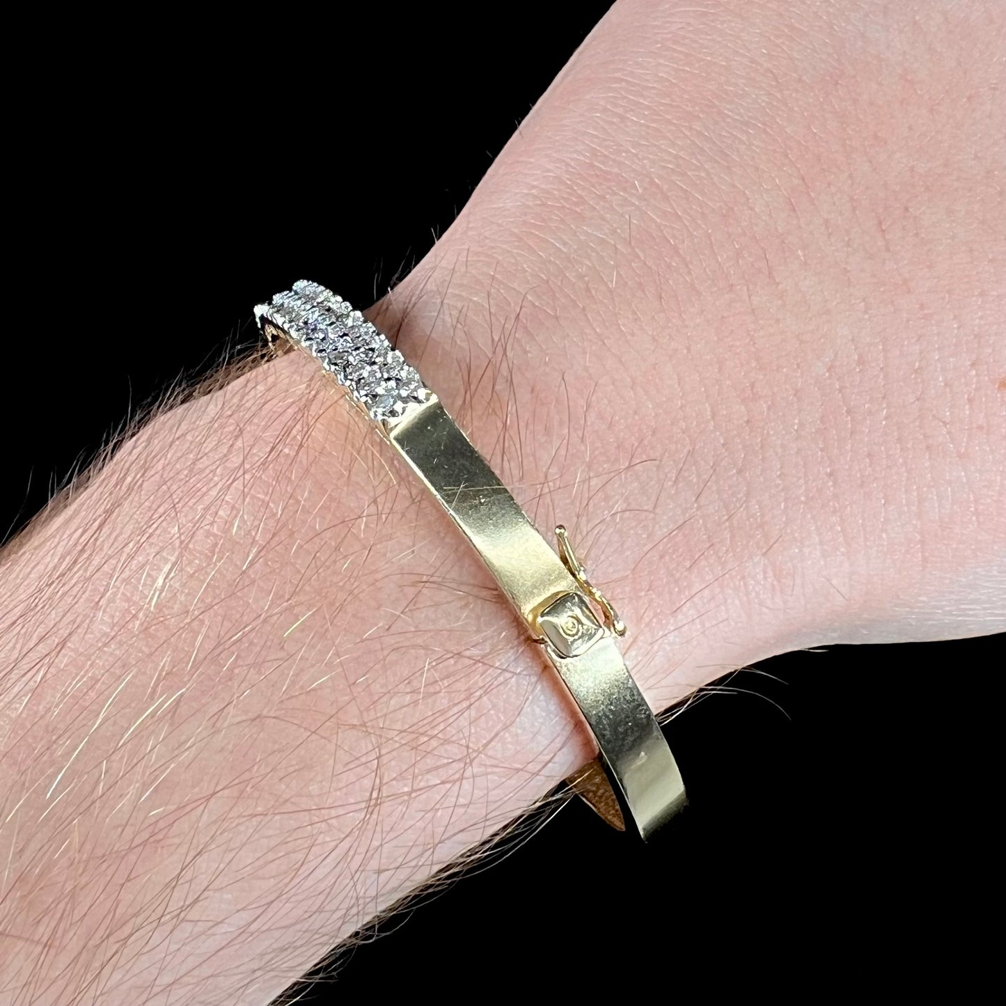 A ladies' hinged yellow gold bangle bracelet set with 50 Standard Round Brilliant Cut diamonds.