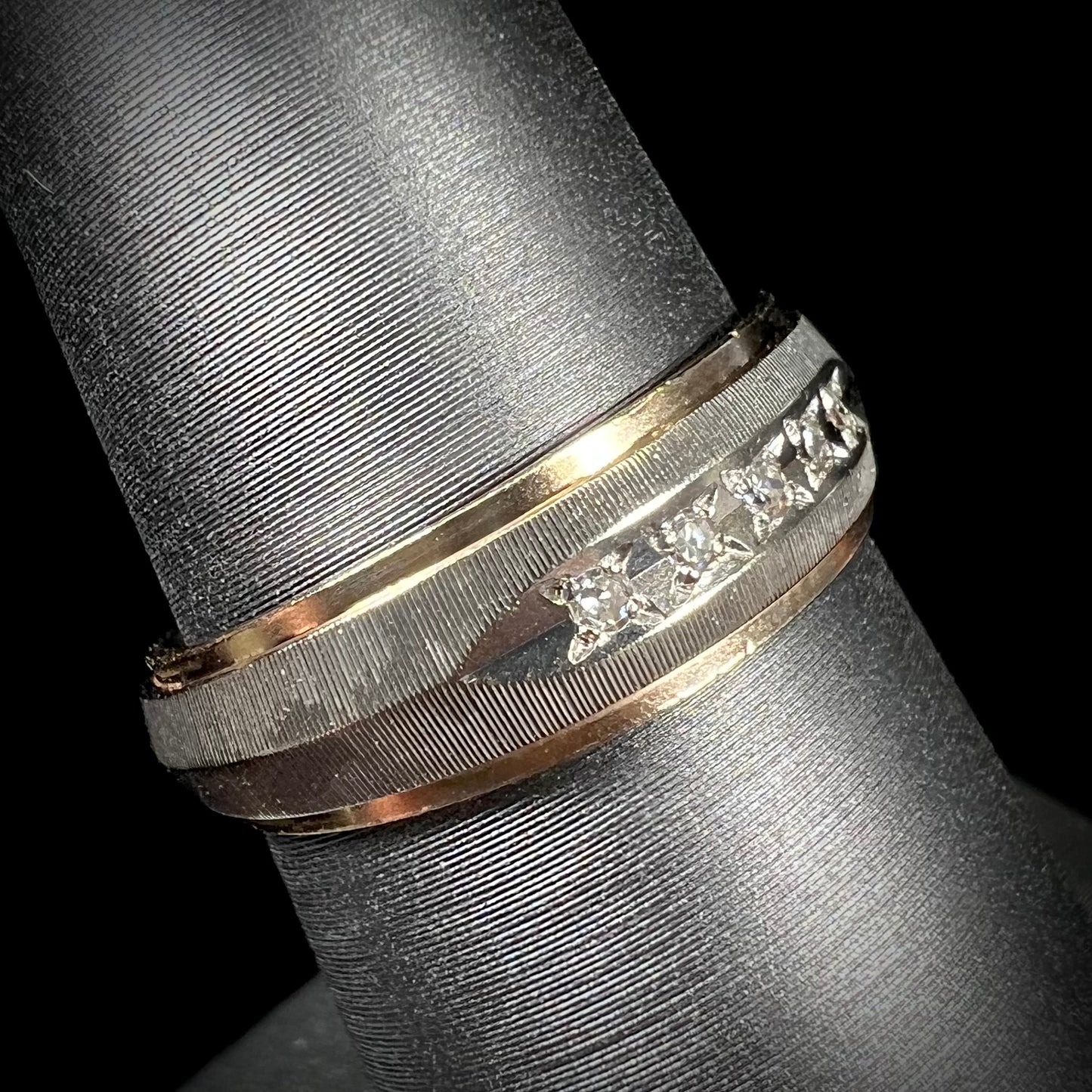 A unisex, two-tone white and yellow gold diamond wedding band. The white gold is textured.