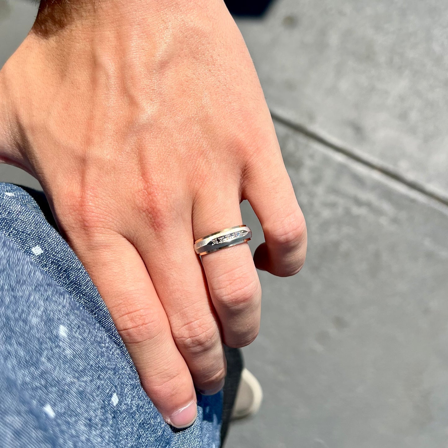 A unisex, two-tone white and yellow gold diamond wedding band. The white gold is textured.
