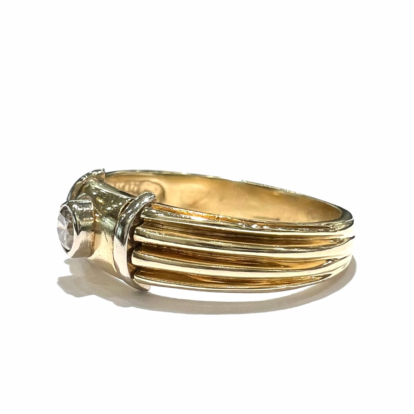 A unisex, vintage style two tone yellow and white gold wedding ring bezel set with a round diamond.