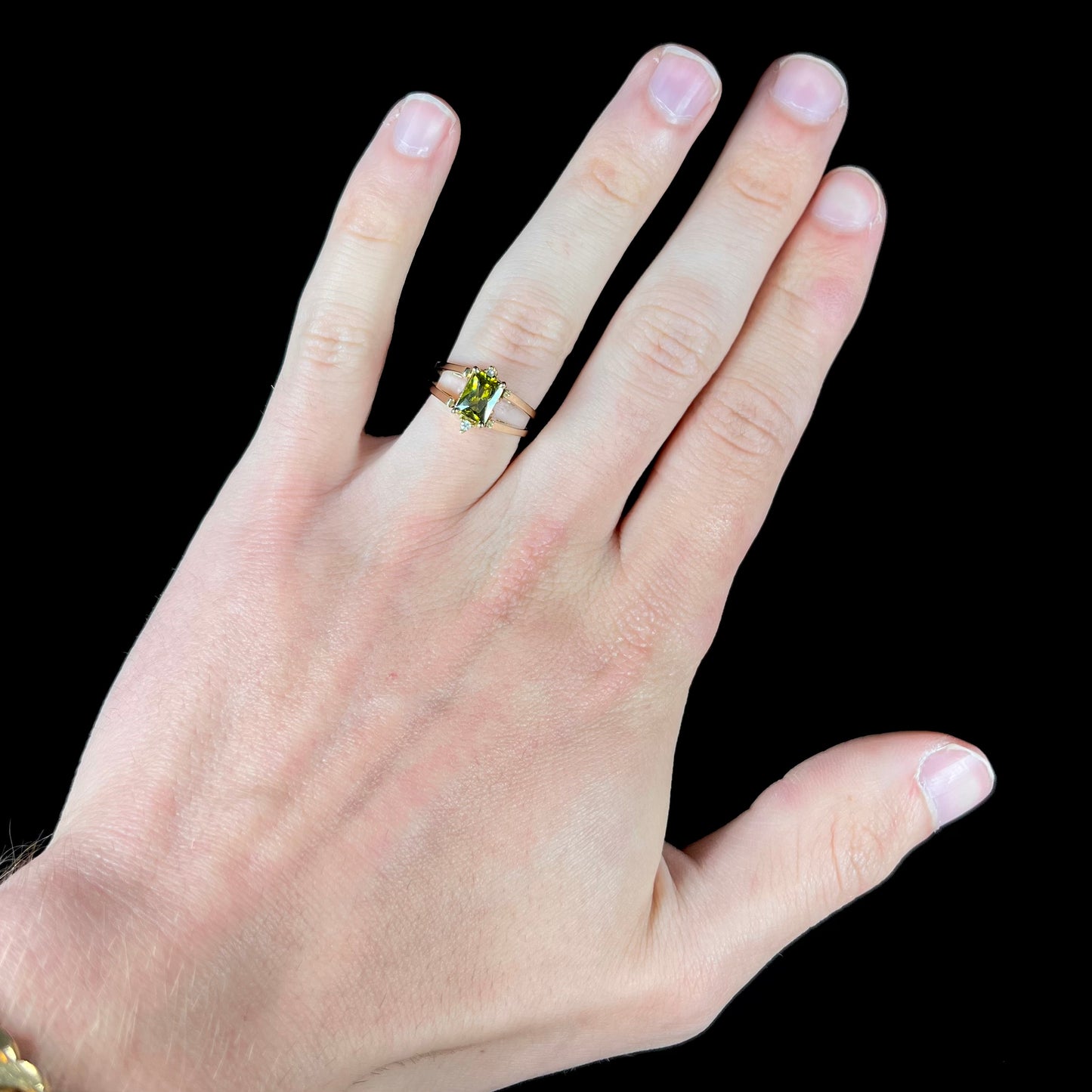 A yellow gold reversible gemstone flip ring. One side of the ring shows a green gemstone, the other shows a cluster of cubic zirconia.