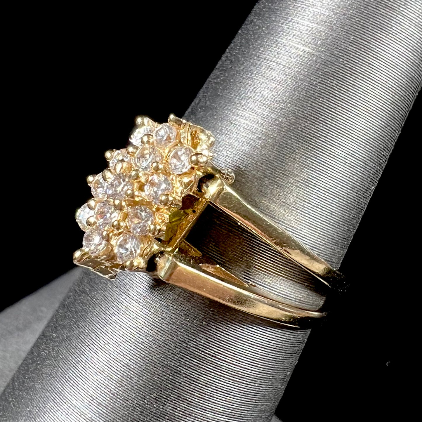 A yellow gold reversible gemstone flip ring. One side of the ring shows a green gemstone, the other shows a cluster of cubic zirconia.