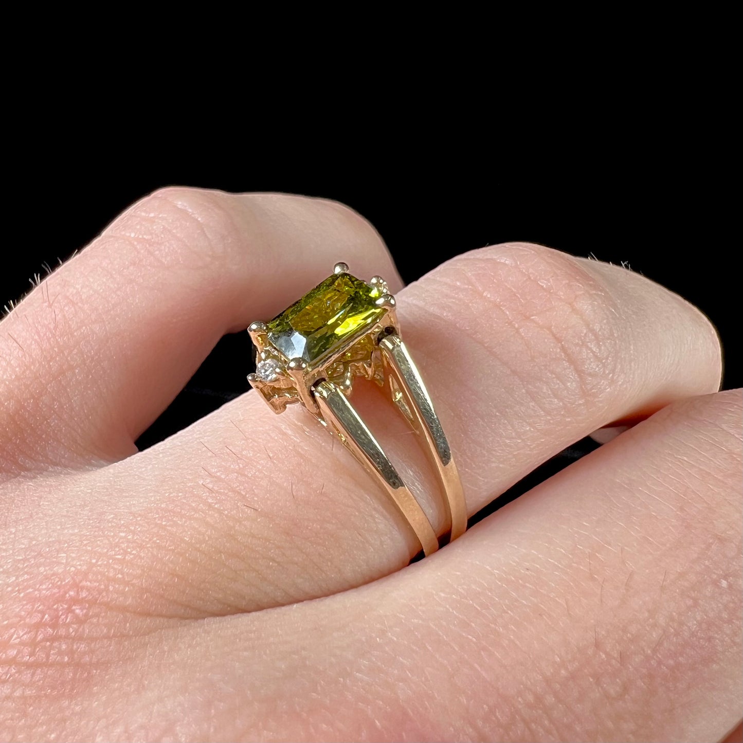 A yellow gold reversible gemstone flip ring. One side of the ring shows a green gemstone, the other shows a cluster of cubic zirconia.
