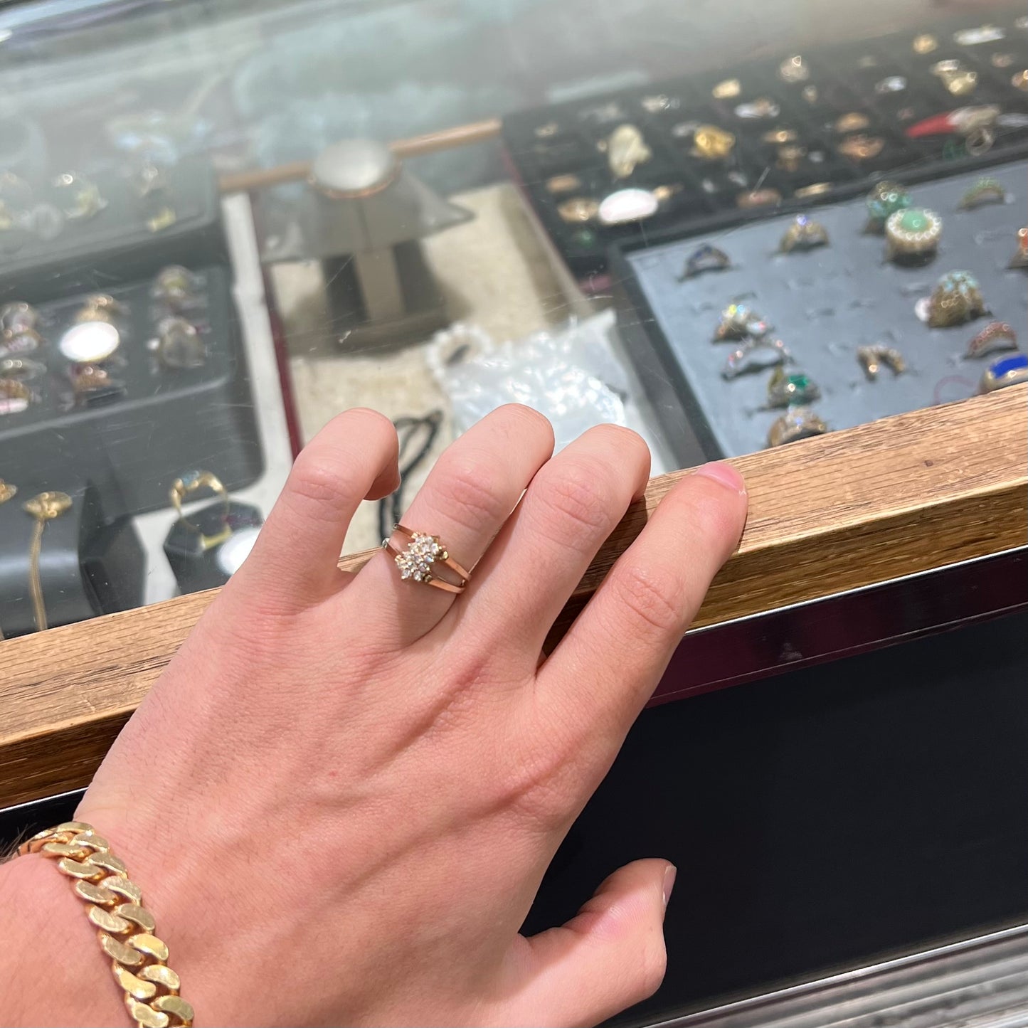 A yellow gold reversible gemstone flip ring. One side of the ring shows a green gemstone, the other shows a cluster of cubic zirconia.