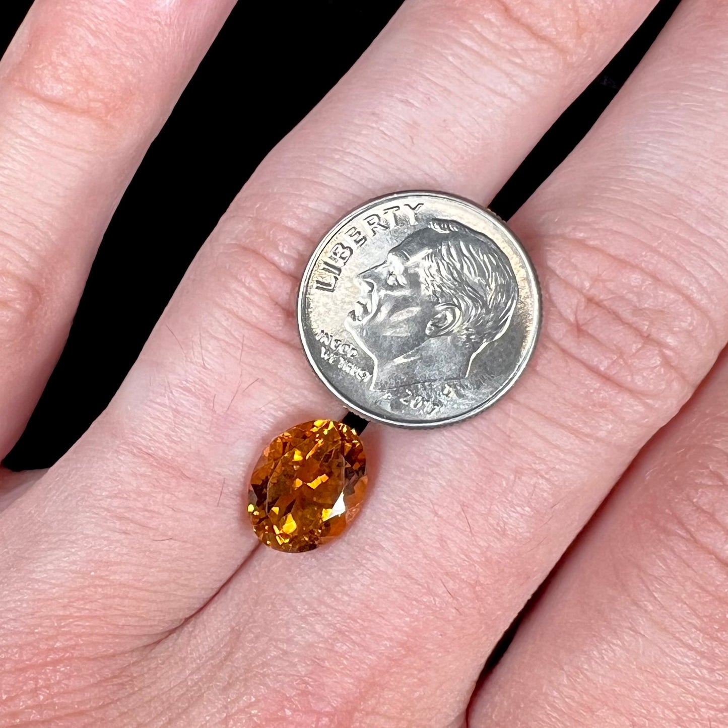 A loose, faceted oval cut orange dravite tourmaline gemstone.