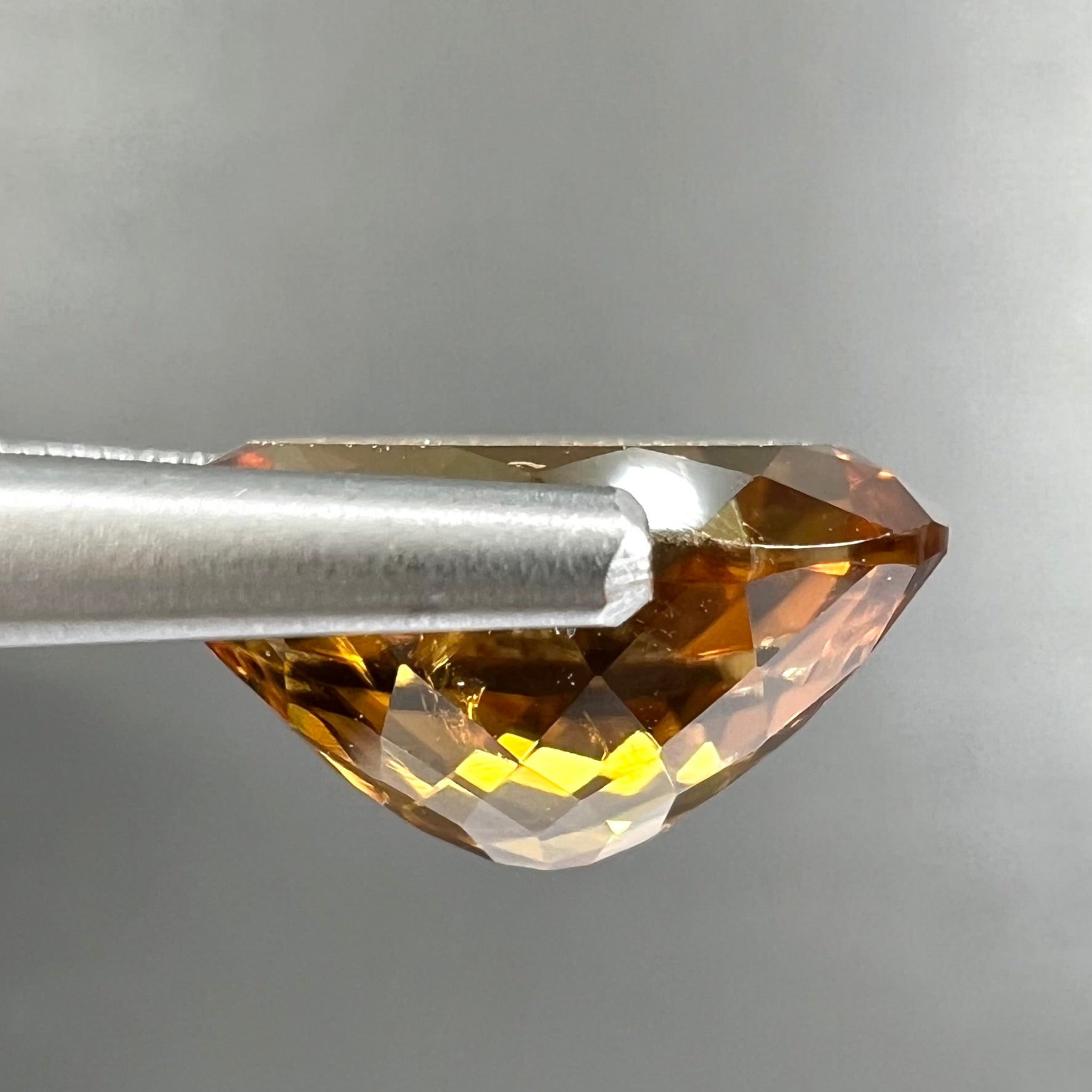 A loose, faceted oval cut orange dravite tourmaline gemstone.