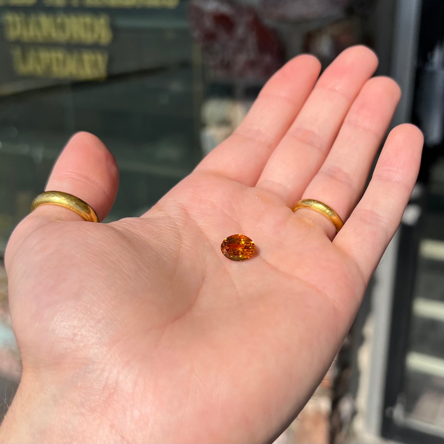 A loose, faceted oval cut orange dravite tourmaline gemstone.