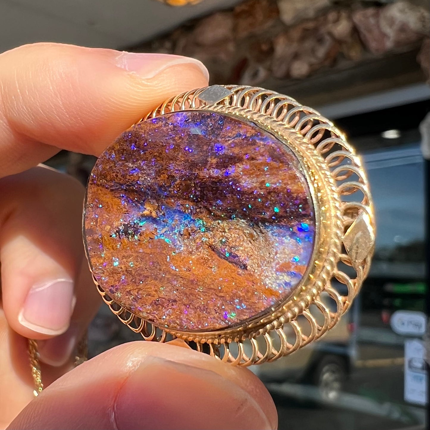 A yellow gold filigree style brooch/pendant combination piece set with a purple opalized wood stone from Duck Creek, Australia.