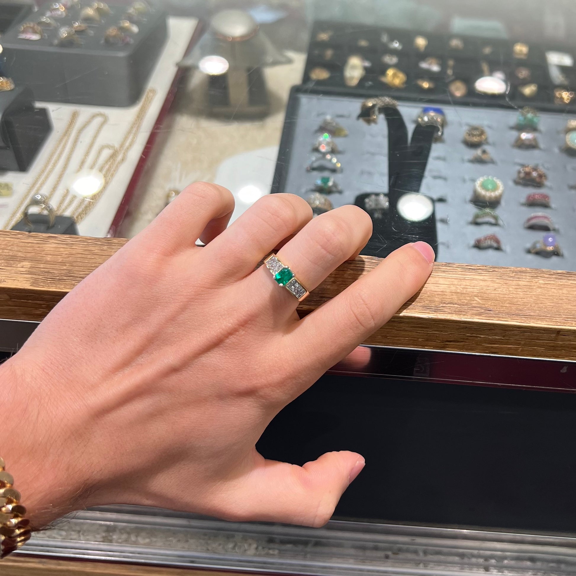 An 18 karat yellow gold ladies' emerald ring, channel set with princess cut diamonds.