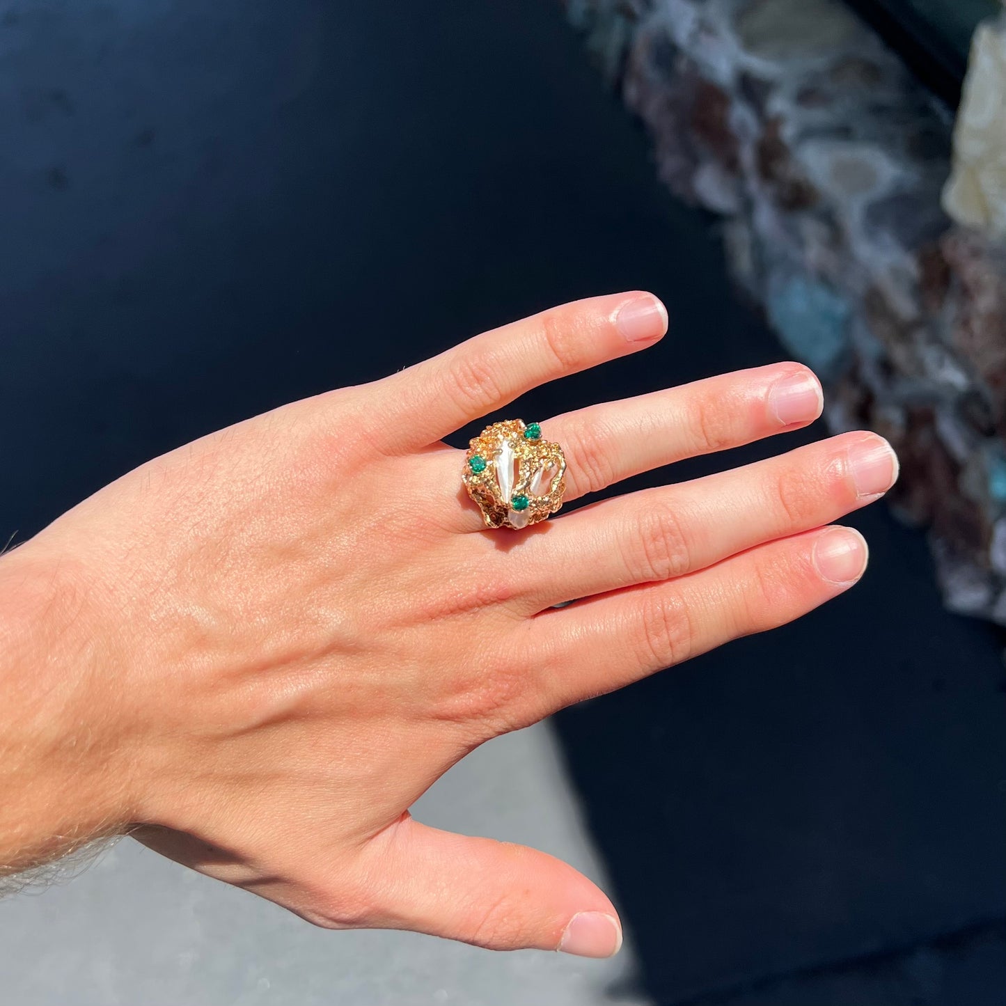 A vintage 1950's gold cluster ring set with freshwater pearls and green imitation emeralds.