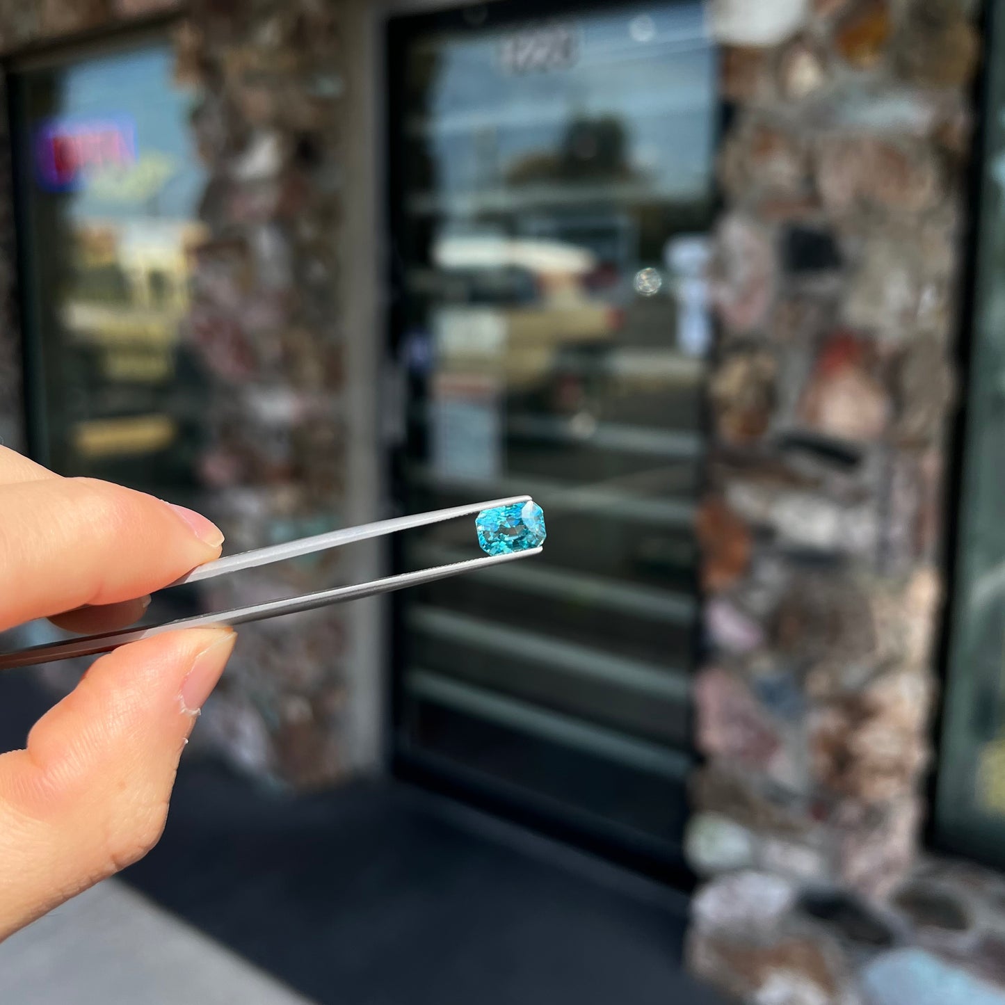 A loose, modified emerald cut blue zircon gemstone. The stone has a large belly.