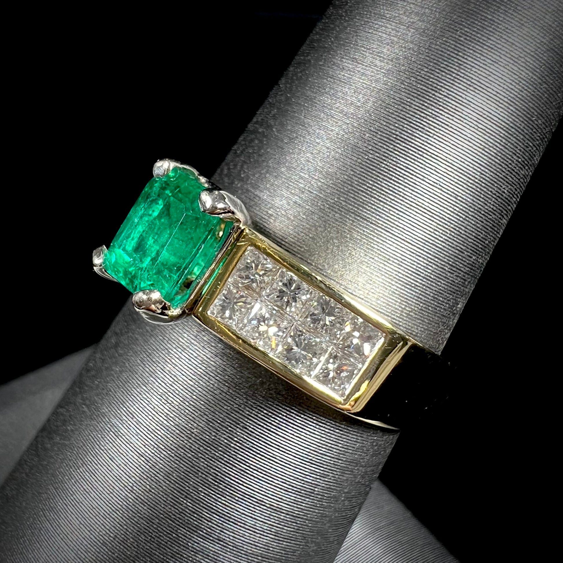 An 18 karat yellow gold ladies' emerald ring, channel set with princess cut diamonds.