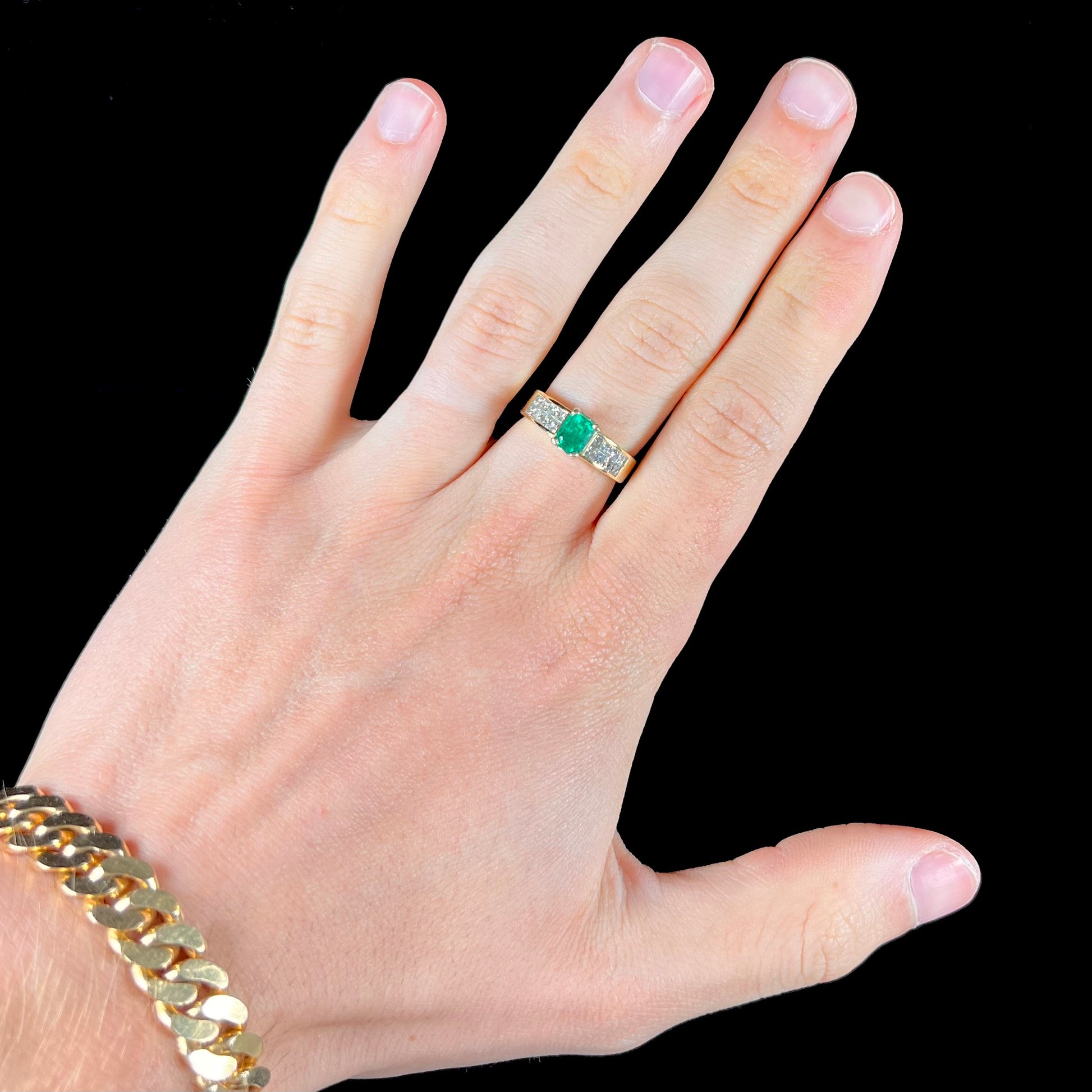 An 18 karat yellow gold ladies' emerald ring, channel set with princess cut diamonds.