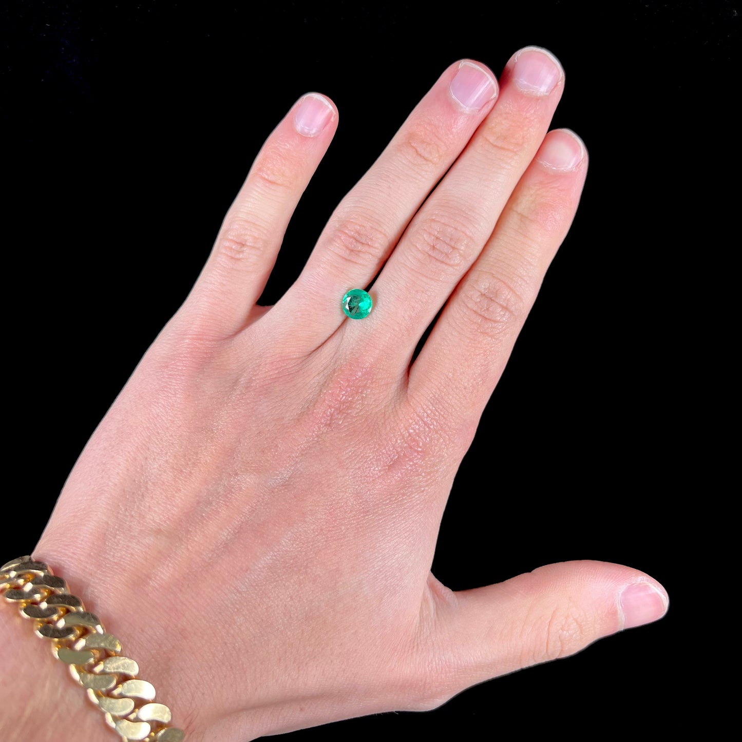 A loose, round brilliant cut natural emerald stone.