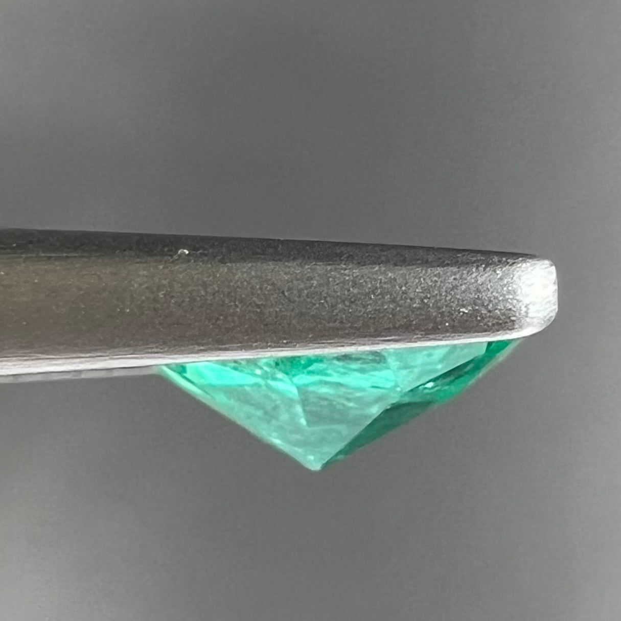 A loose, round brilliant cut natural emerald stone.
