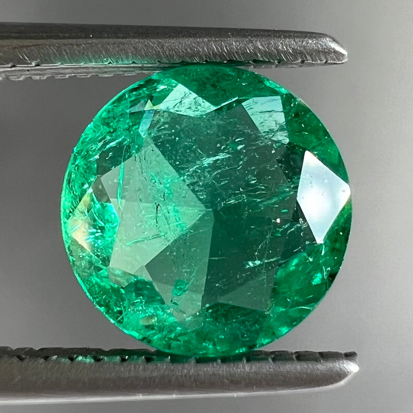 A loose, round brilliant cut natural emerald stone.