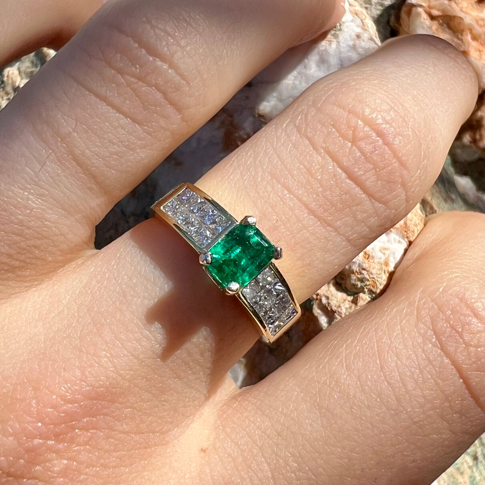 An 18 karat yellow gold ladies' emerald ring, channel set with princess cut diamonds.