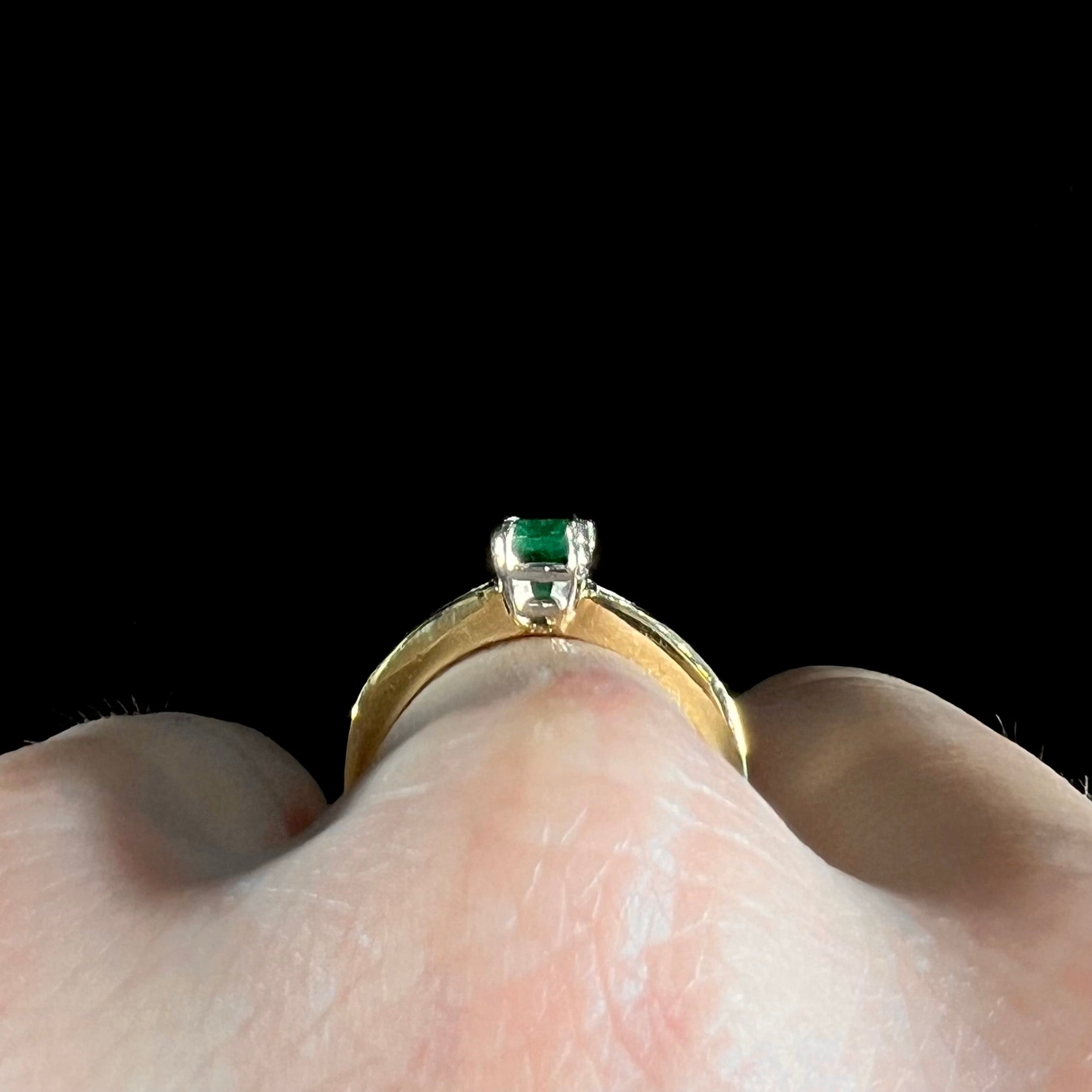 An 18 karat yellow gold ladies' emerald ring, channel set with princess cut diamonds.