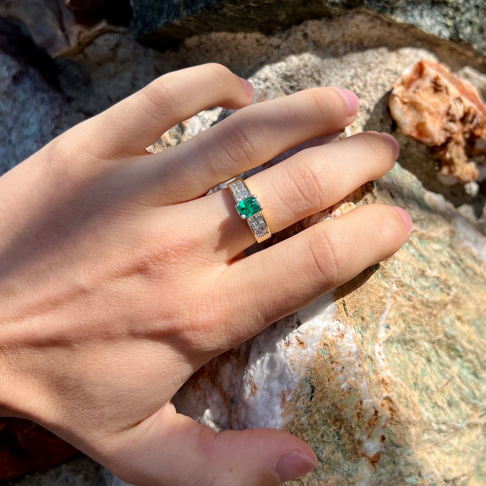 An 18 karat yellow gold ladies' emerald ring, channel set with princess cut diamonds.