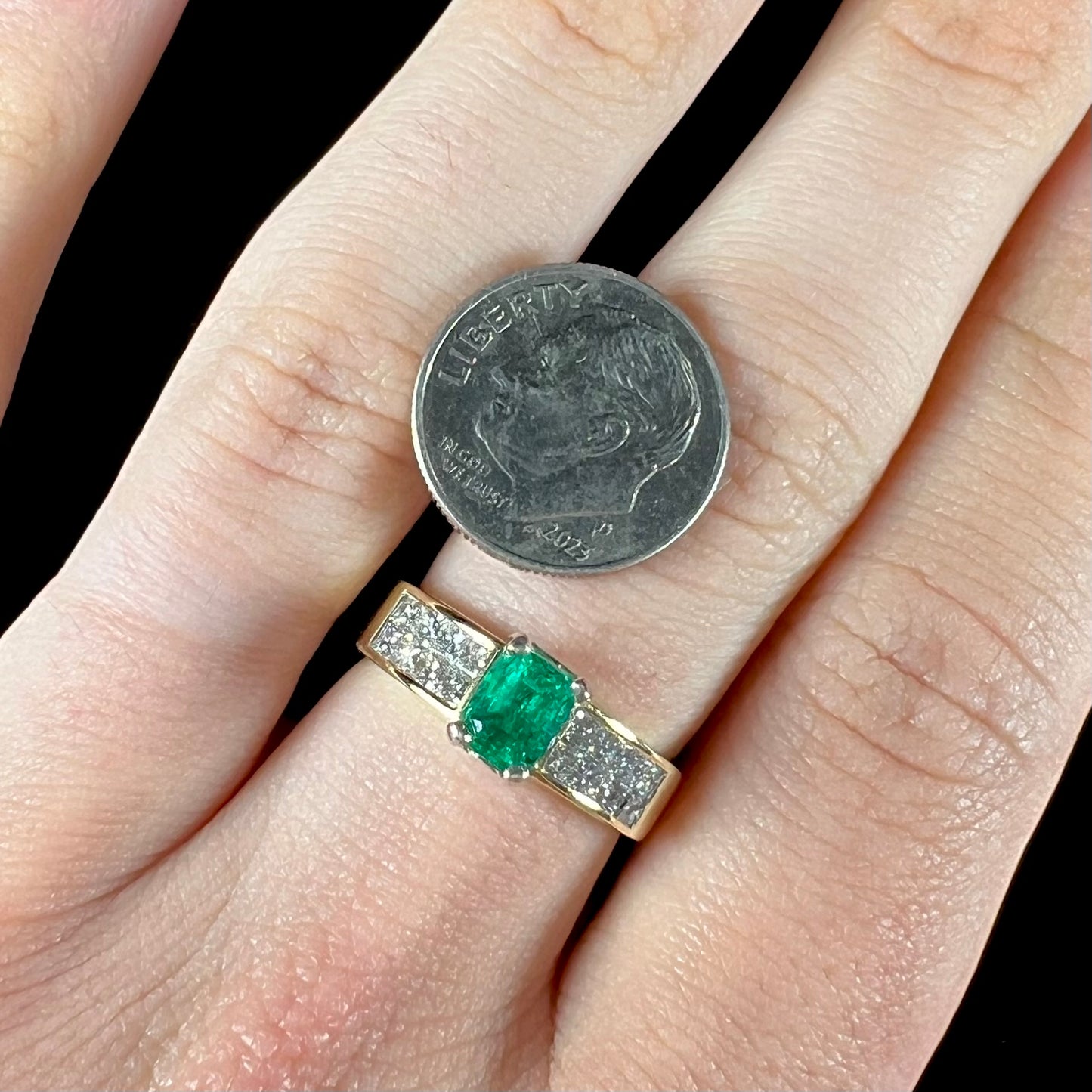 An 18 karat yellow gold ladies' emerald ring, channel set with princess cut diamonds.