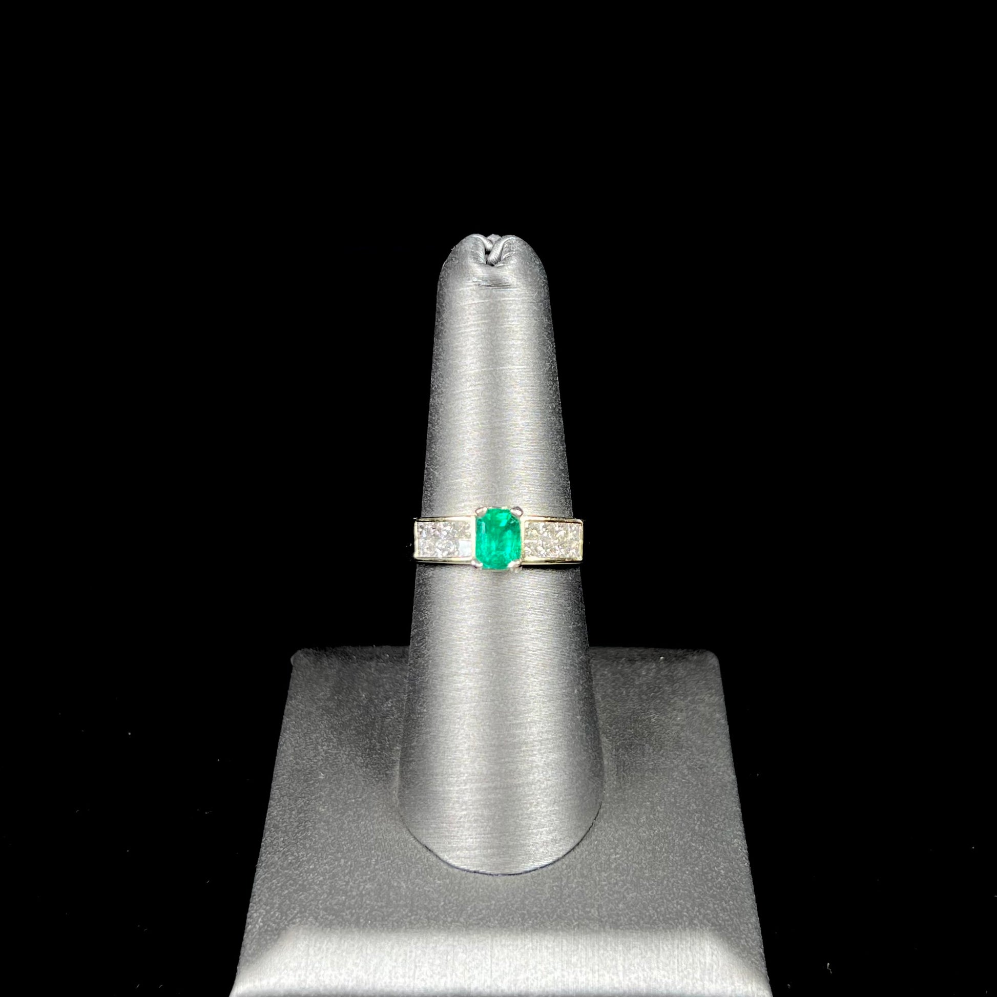 An 18 karat yellow gold ladies' emerald ring, channel set with princess cut diamonds.