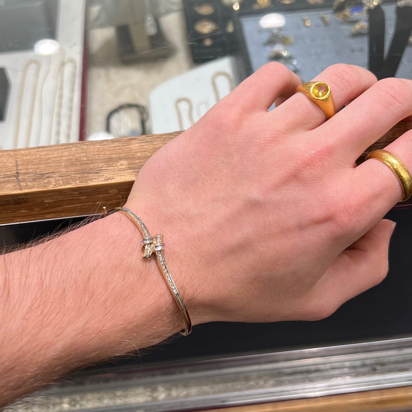 A ladies' knot style yellow gold bangle bracelet set with round and baguette cut diamonds.