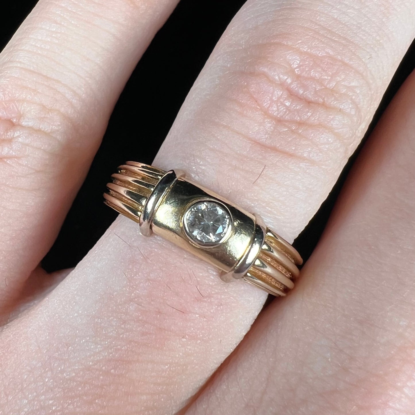 A unisex, vintage style two tone yellow and white gold wedding ring bezel set with a round diamond.