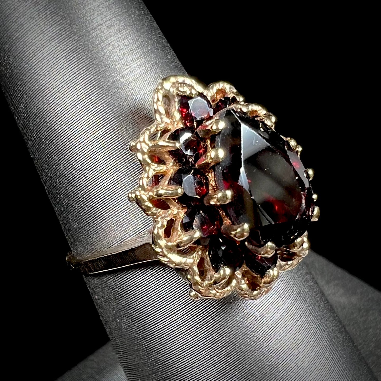 A vintage, 1940's style yellow gold ring set with a pear shaped almandine garnet. A halo of round garnets surround the center stone.