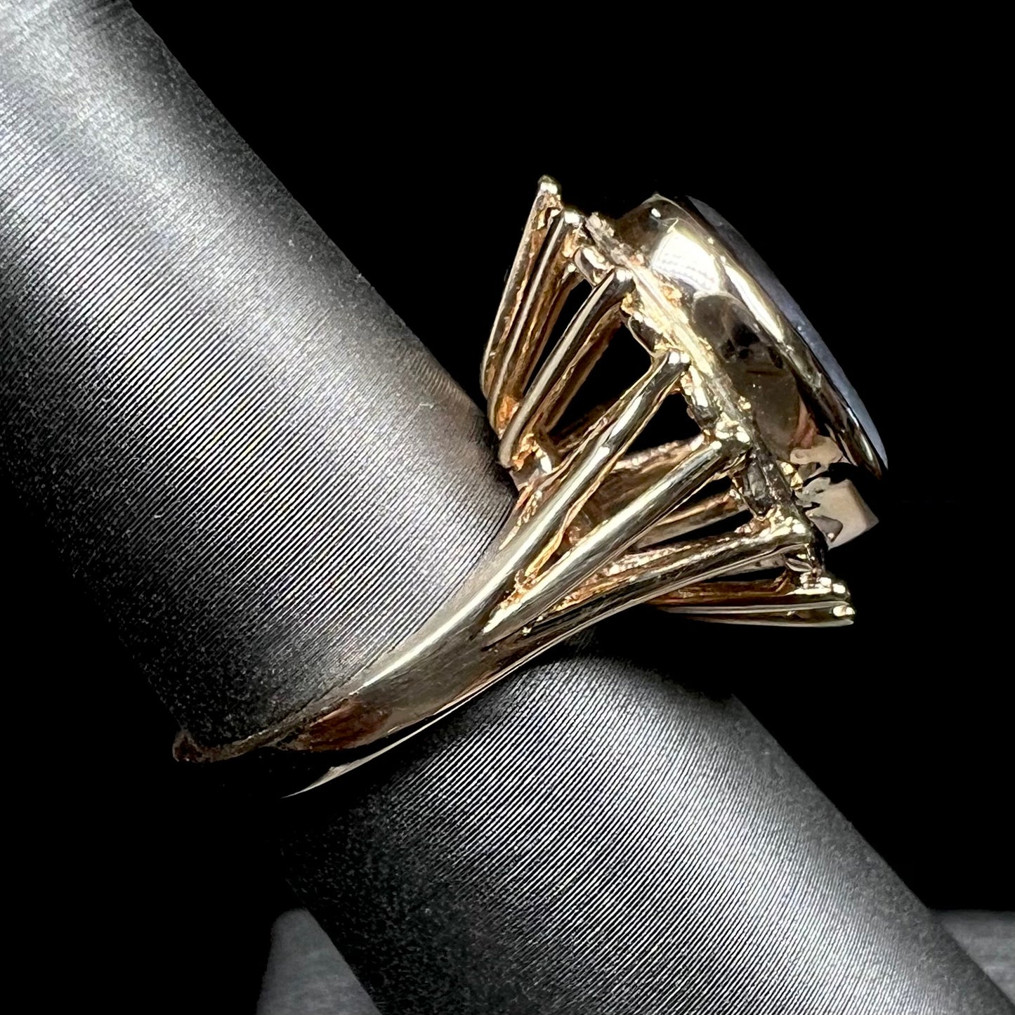 A ladies' yellow gold solitaire ring mounted with a gray trapiche star sapphire.