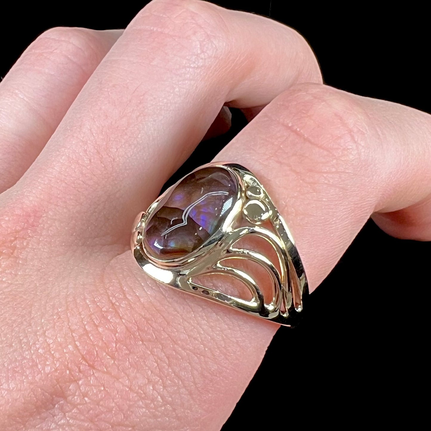 A men's yellow gold fire agate ring.  The fire agate is blue and purple with light scratches.